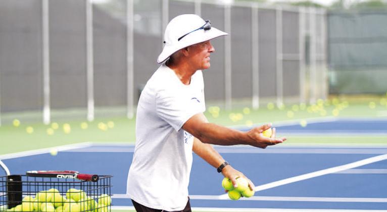 HUNTER KING | DISPATCH RECORD Kenneth Peiser flips balls to young players as he teaches them about forehands and backhands.