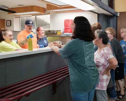 Kempner Volunteer Fire Department volunteers Casey Chapman and Alex Hansen, left and second from left, serve hungry fundraiser attendees at the annual BBQ and Auction event on Saturday. The fundraiser regularly garners thousands of dollars for fire department equipment, operation and training. gabriela sangache | dispatch record